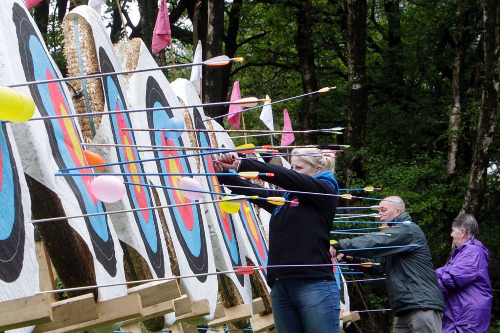 Archers pulling arrows from a line of targets filled with arrows